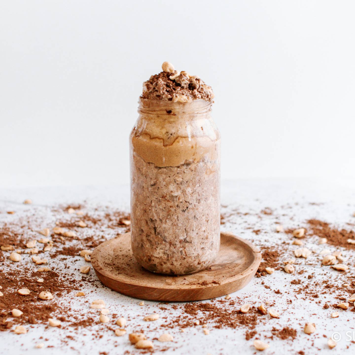 Chocolate peanut butter overnight oats in a glass jar with peanut butter and cocoa powder.