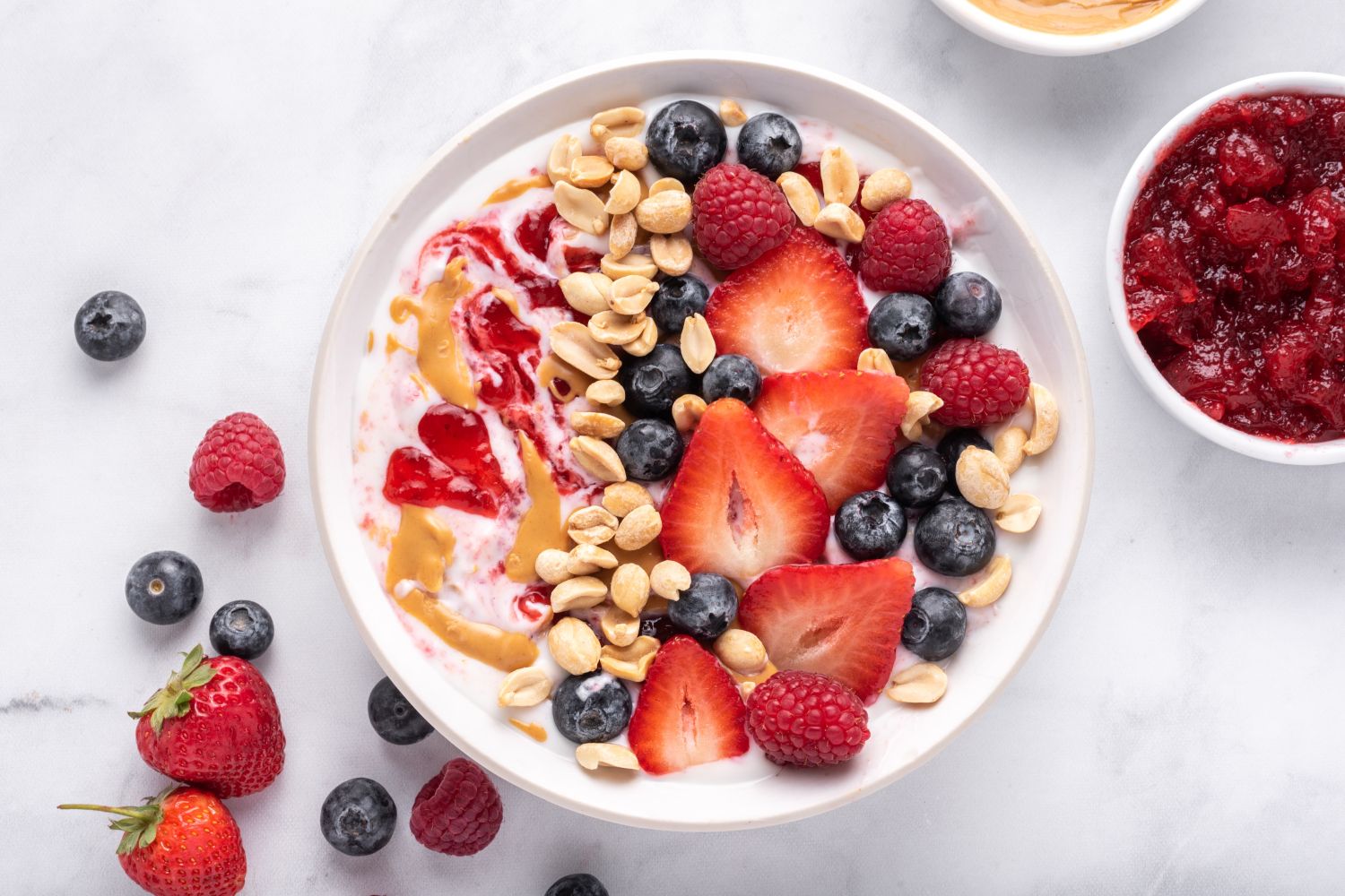 Peanut butter and jelly yogurt bowl with peanut butter, strawberry jelly, peanuts, and fresh fruit.