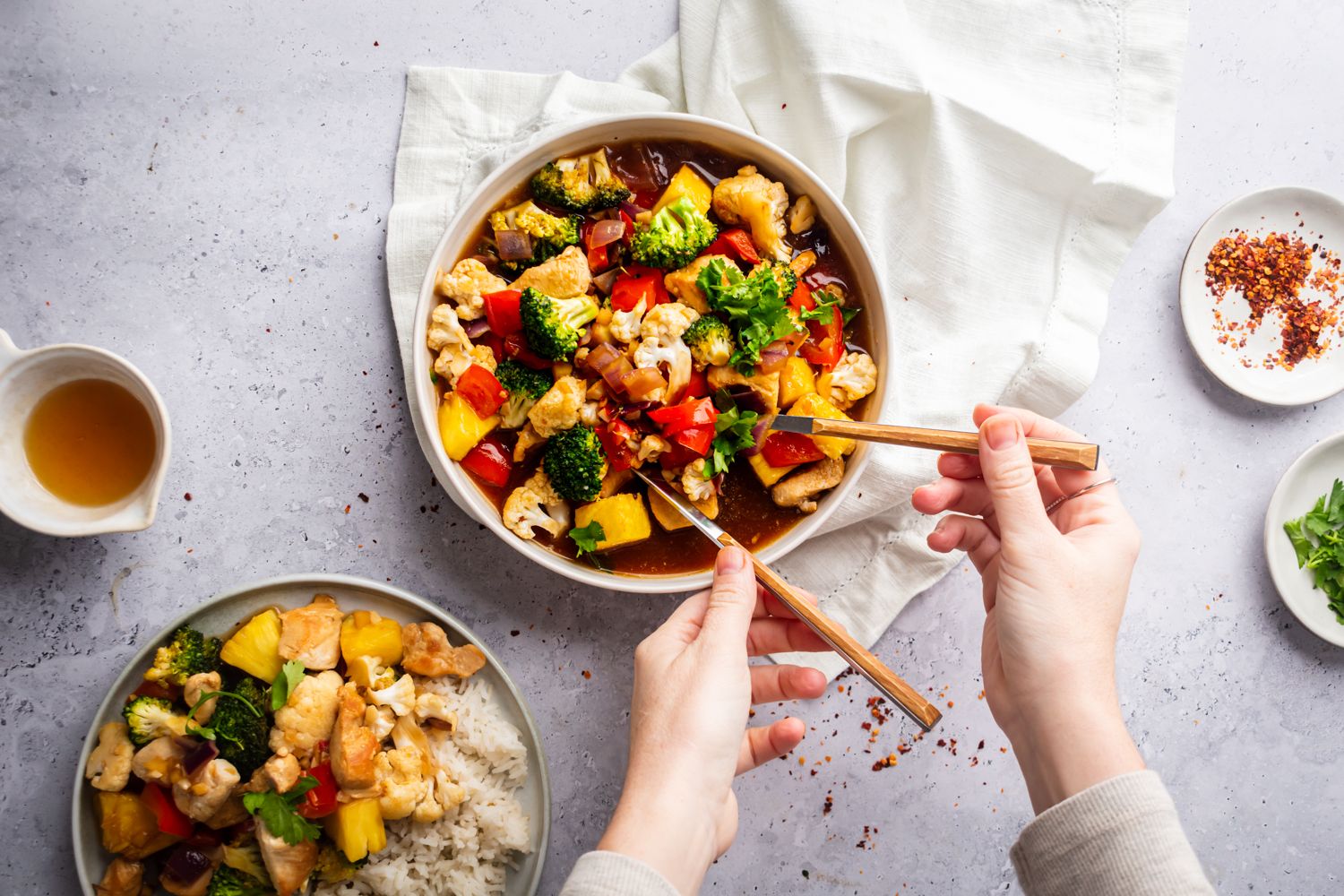 Chicken and pineapple stir fry in a bowl with broccoli, cauliflower, red onion, pineapple, and cilantro in stir fry sauce.