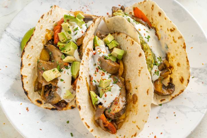 Portobello mushroom fajitas with peppers, onions, mushrooms, guacamole, and sour cream in a warm corn tortilla.