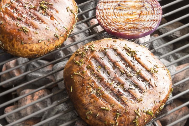 Portobello mushroom buns with grill marks on a grill.