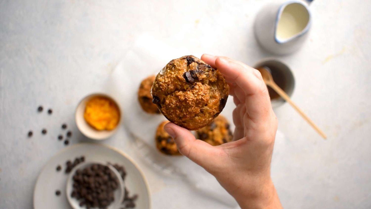 Oatmeal pumpkin muffins with chocolate chips being held up by a hand.