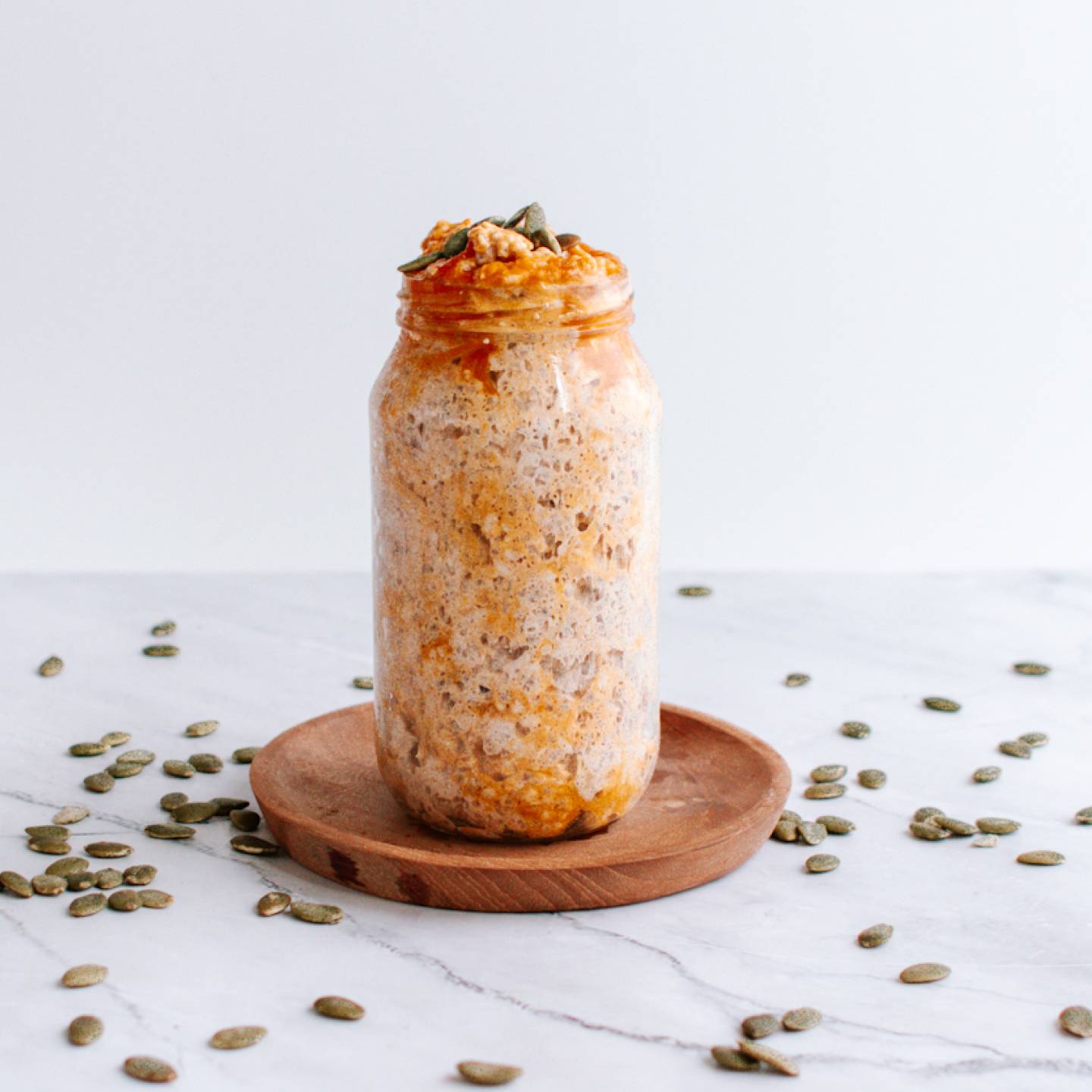 Pumpkin overnight oatmeal in a mason jar with pumpkin seeds, pumpkin puree, and cinnamon.