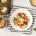 Quiche cupcakes with a ham crust and a cheese and spinach filling on a wire rack with cracked eggs on the side. 