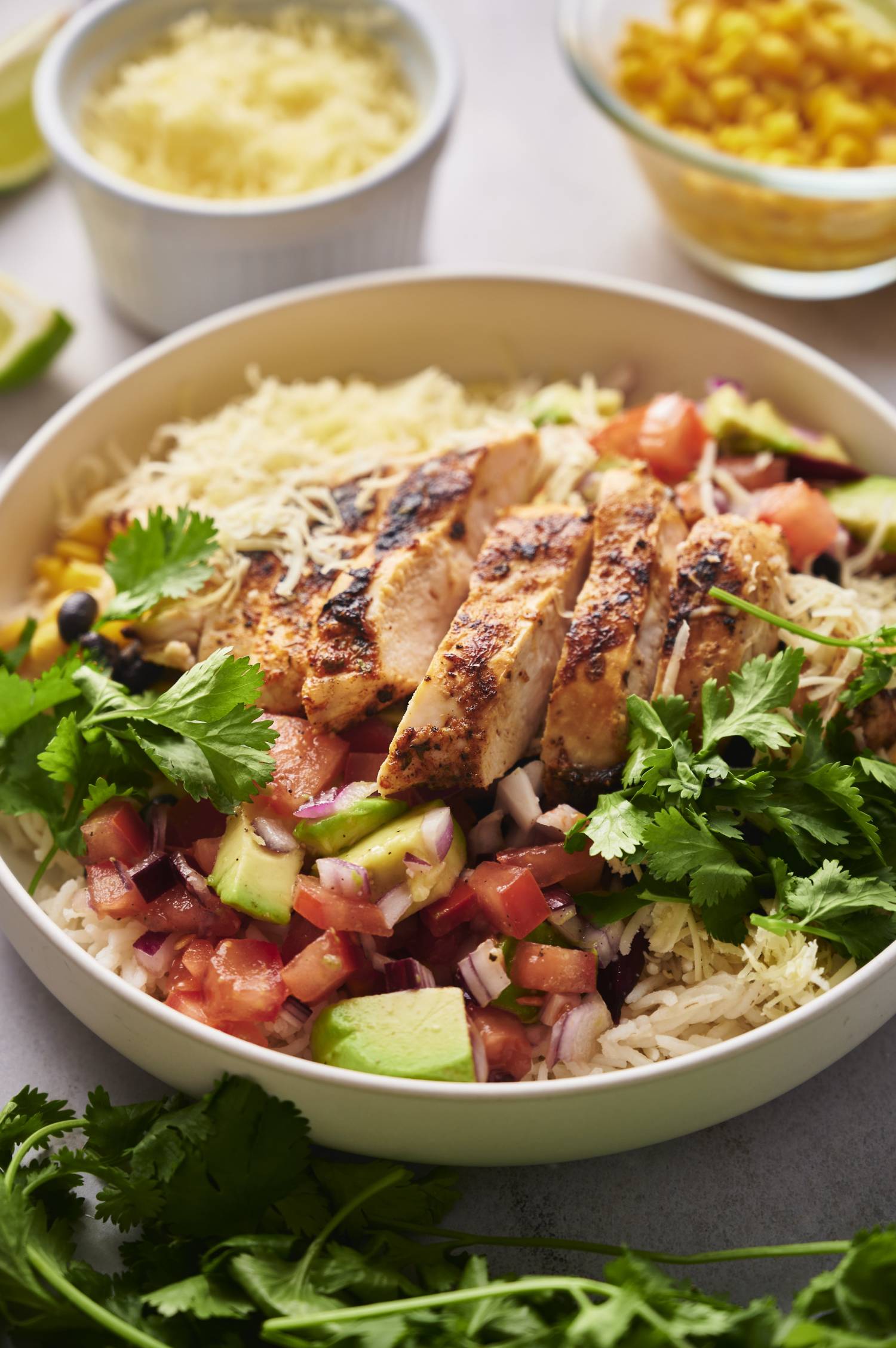 Easy chicken and rice bowls with black beans, corn, and salsa served with cilantro and cheese. 