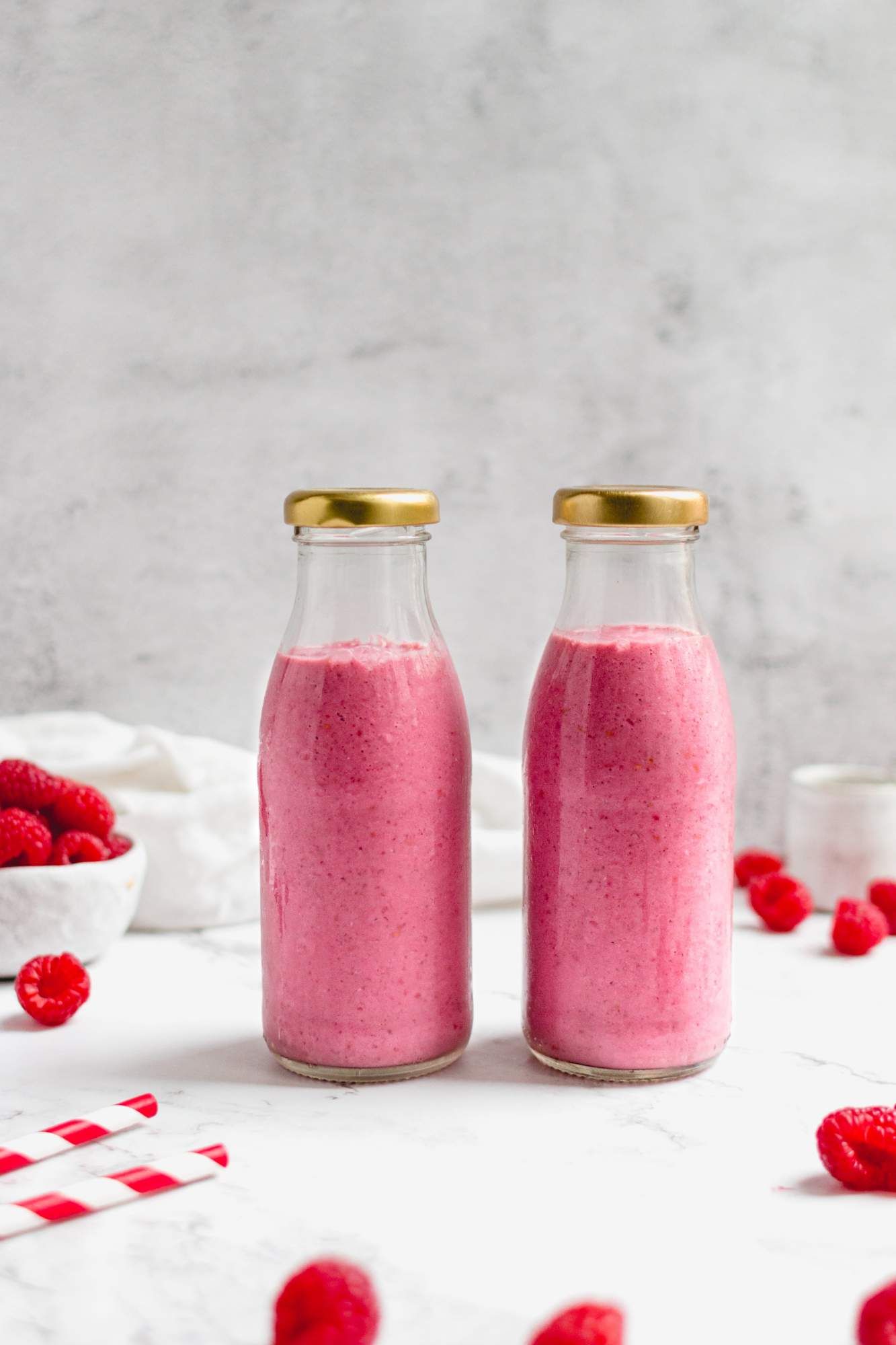 Chia and raspberry smoothie in two glass jars with raspberries  on the side.