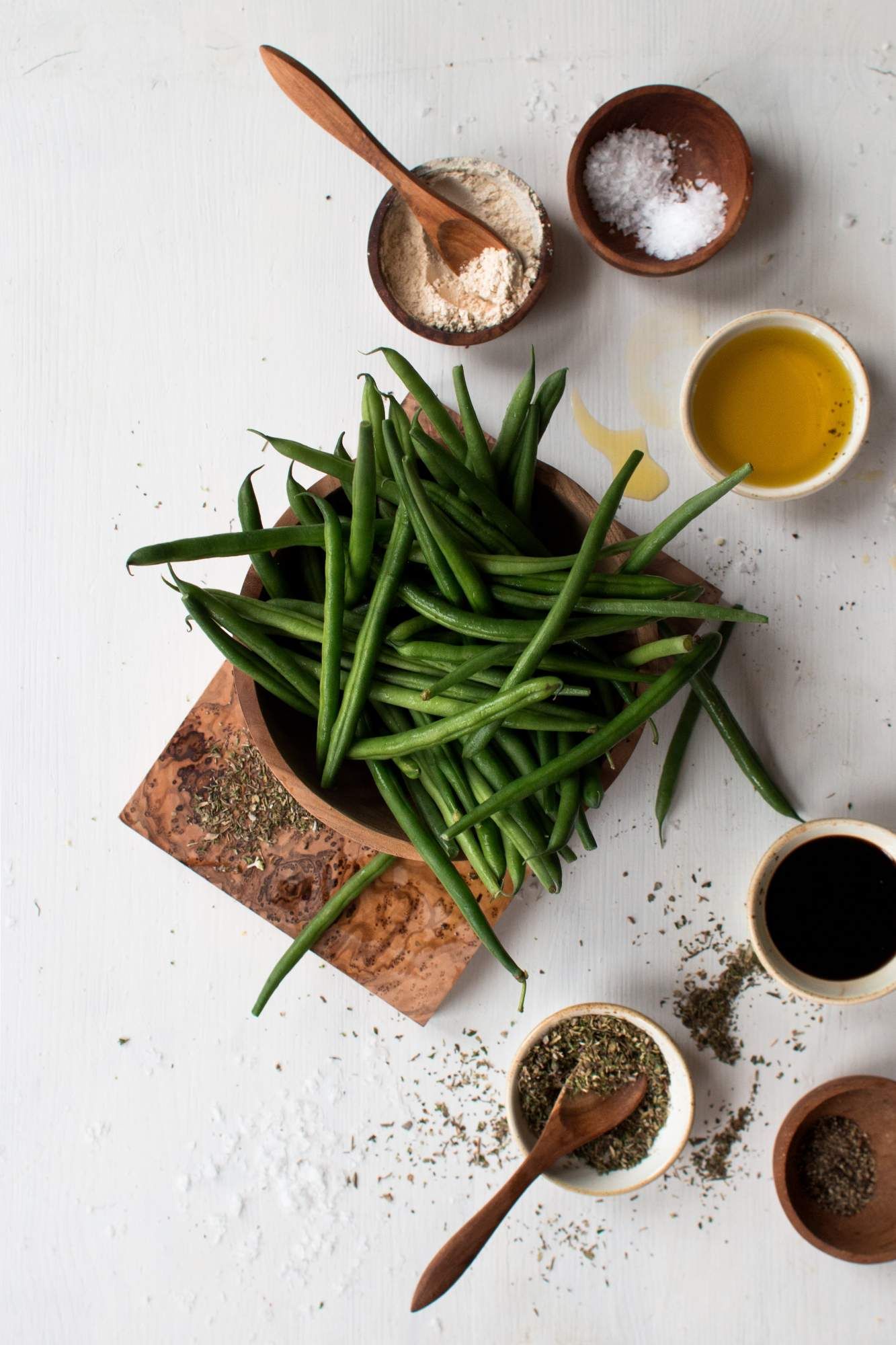 Ingredients for roasting green beans including green beans, oil, garlic powder, Italian seasoning, vinegar, salt, and pepper.