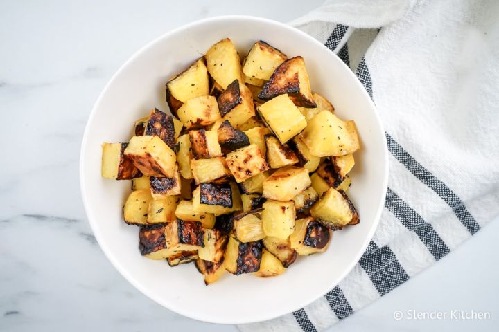 Roasted turnips with olive oil in a white bowl with a blue napkin.