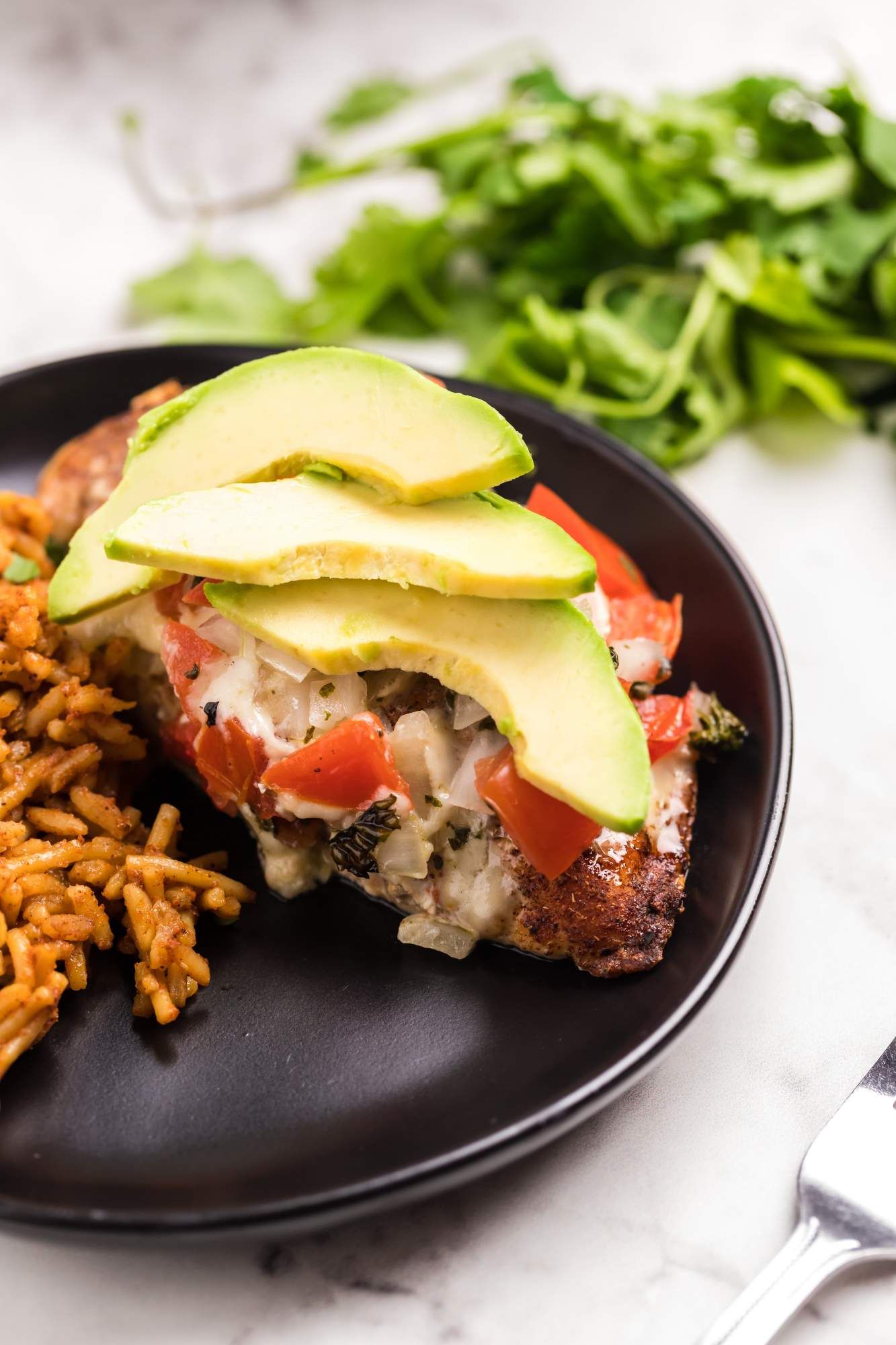 Chicken breast cooked in salsa and served with rice and avocado.