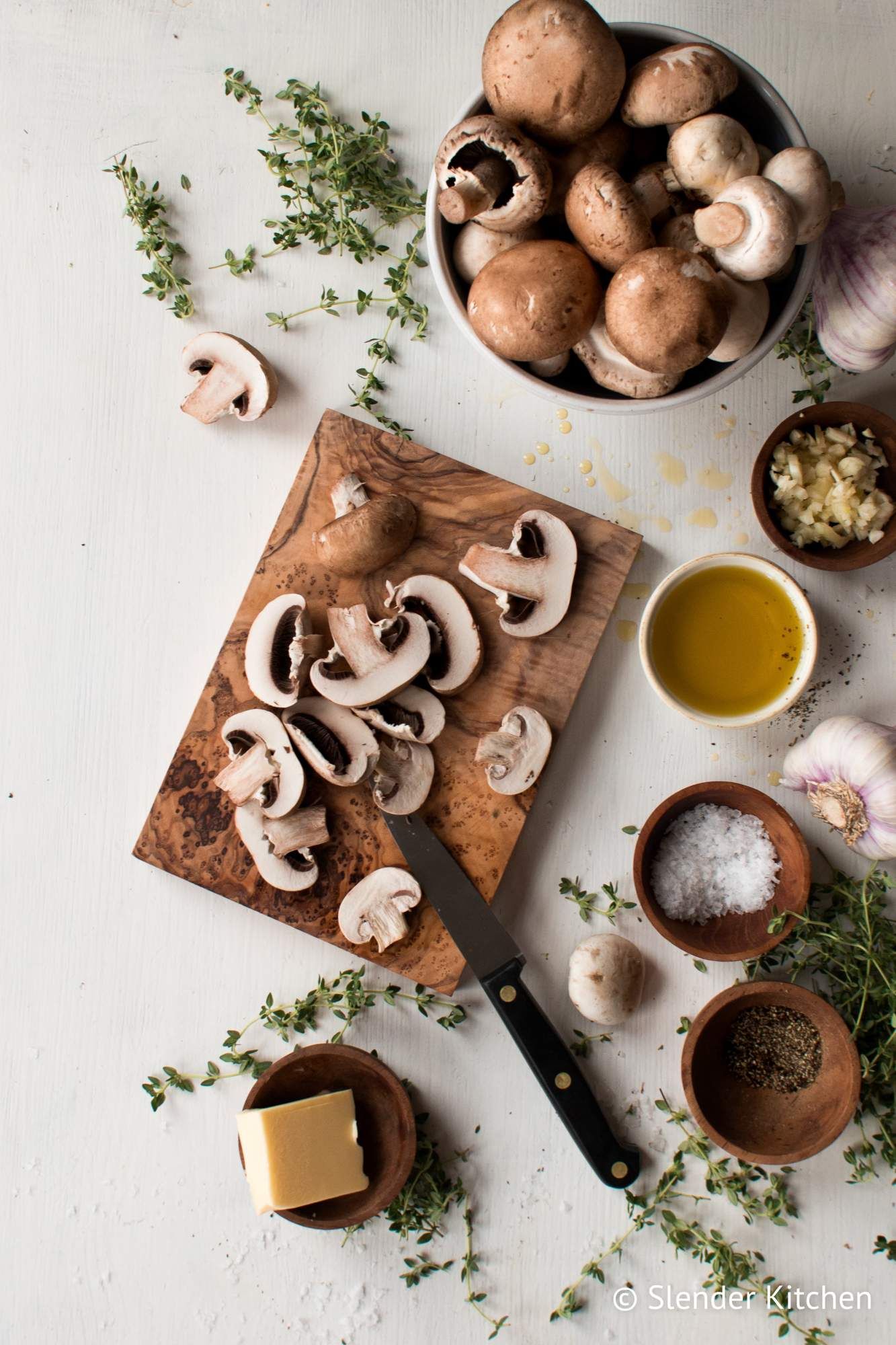 Ingredients for sauteed mushrooms including sliced mushrooms, olive oil, garlic, butter, thyme, salt, and pepper.