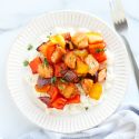 Sheet pan honey Sriracha chicken and vegetables on a white plate with rice.