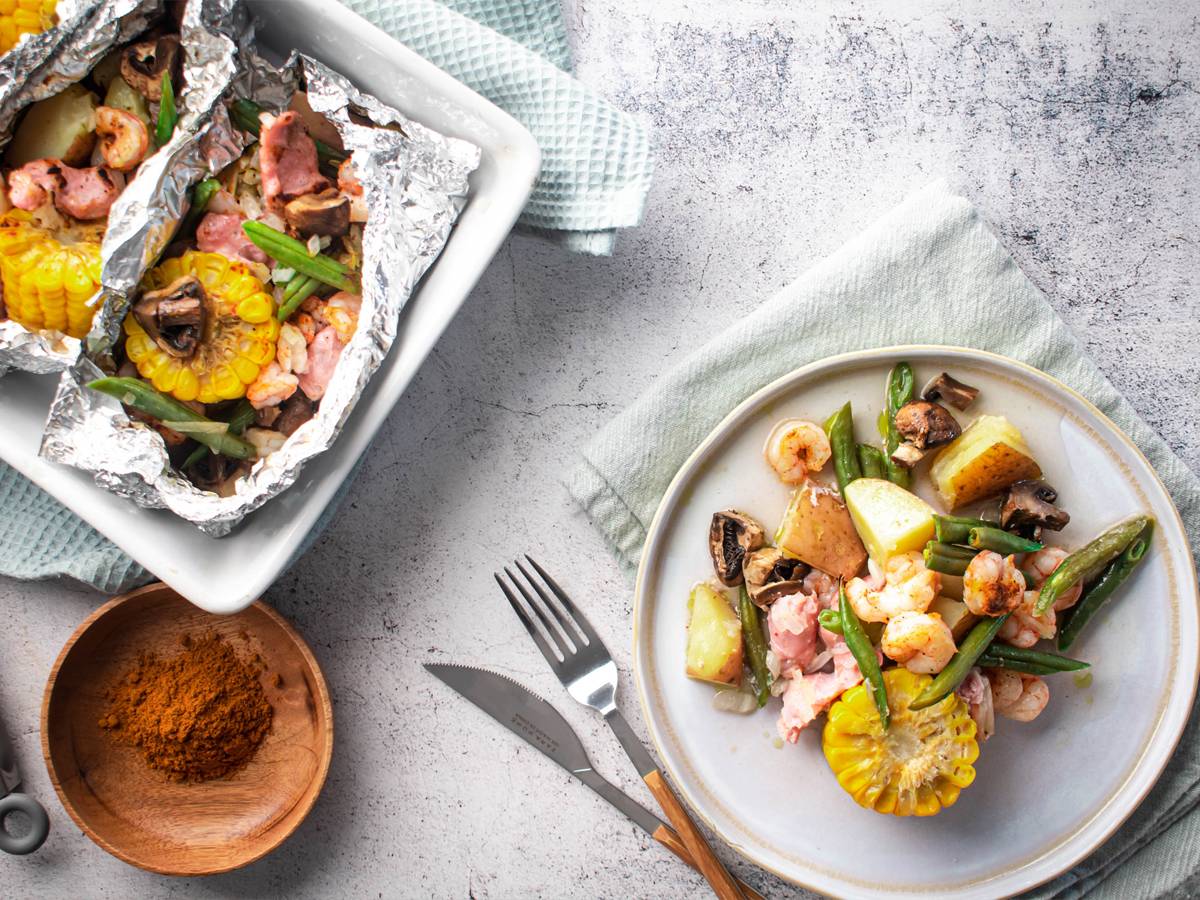 Shrimp boil foil packets with shrimp, andouille sausage, corn, green beans, potatoes, onions, and mushrooms in Cajun seasoning.