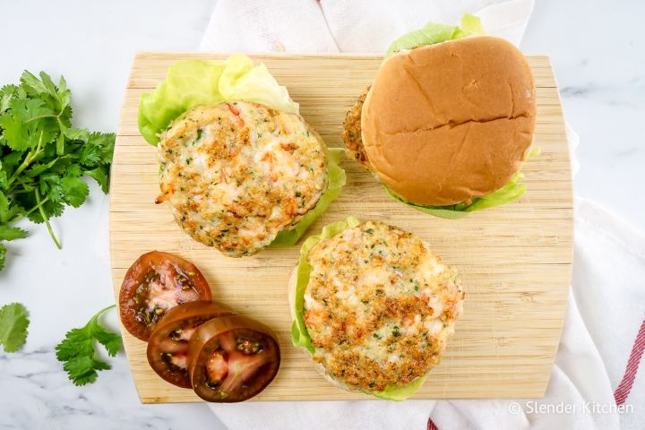 Shrimp burgers with lettuce and tomatoes on a wheat bun.