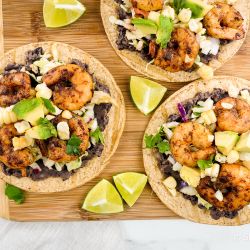 Shrimp tostadas with black beans, cabbage, spiced shrimp, avocado, and corn on baked tortillas.