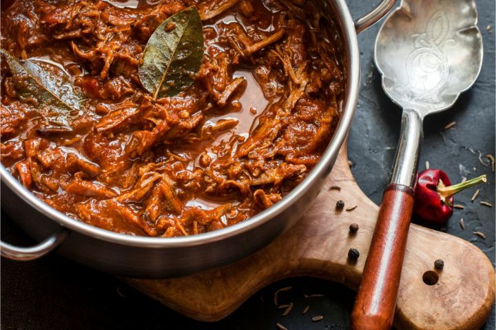 Slow cooker beef rago with shredded beef, tomato sauce, and fresh basil.