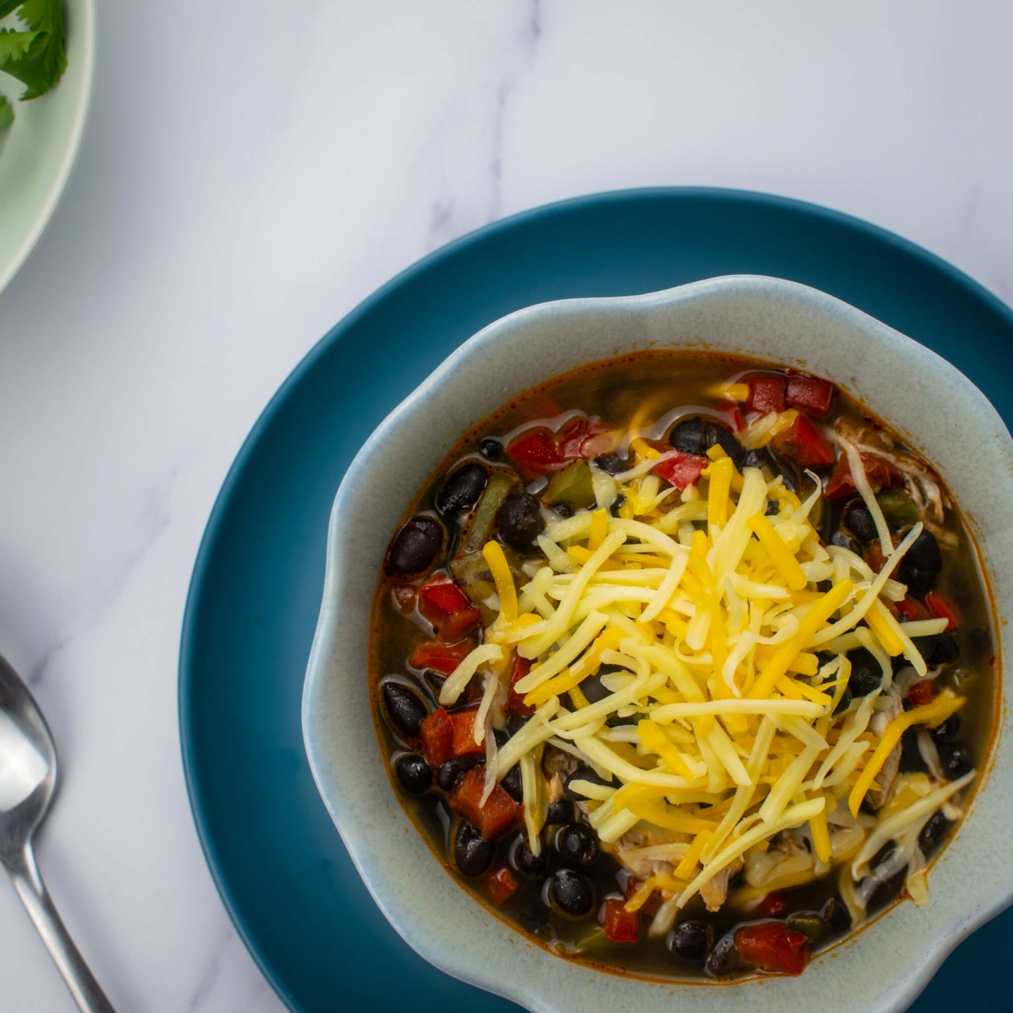 Slow Cooker Chicken Enchilada Soup with shredded cheese and cilantro.