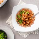 Slow cooker frijoles charros, cowboy beans, in a bowl with creamy pinto beans, jalapenoes, tomatoes, onions, and fresh cilantro.