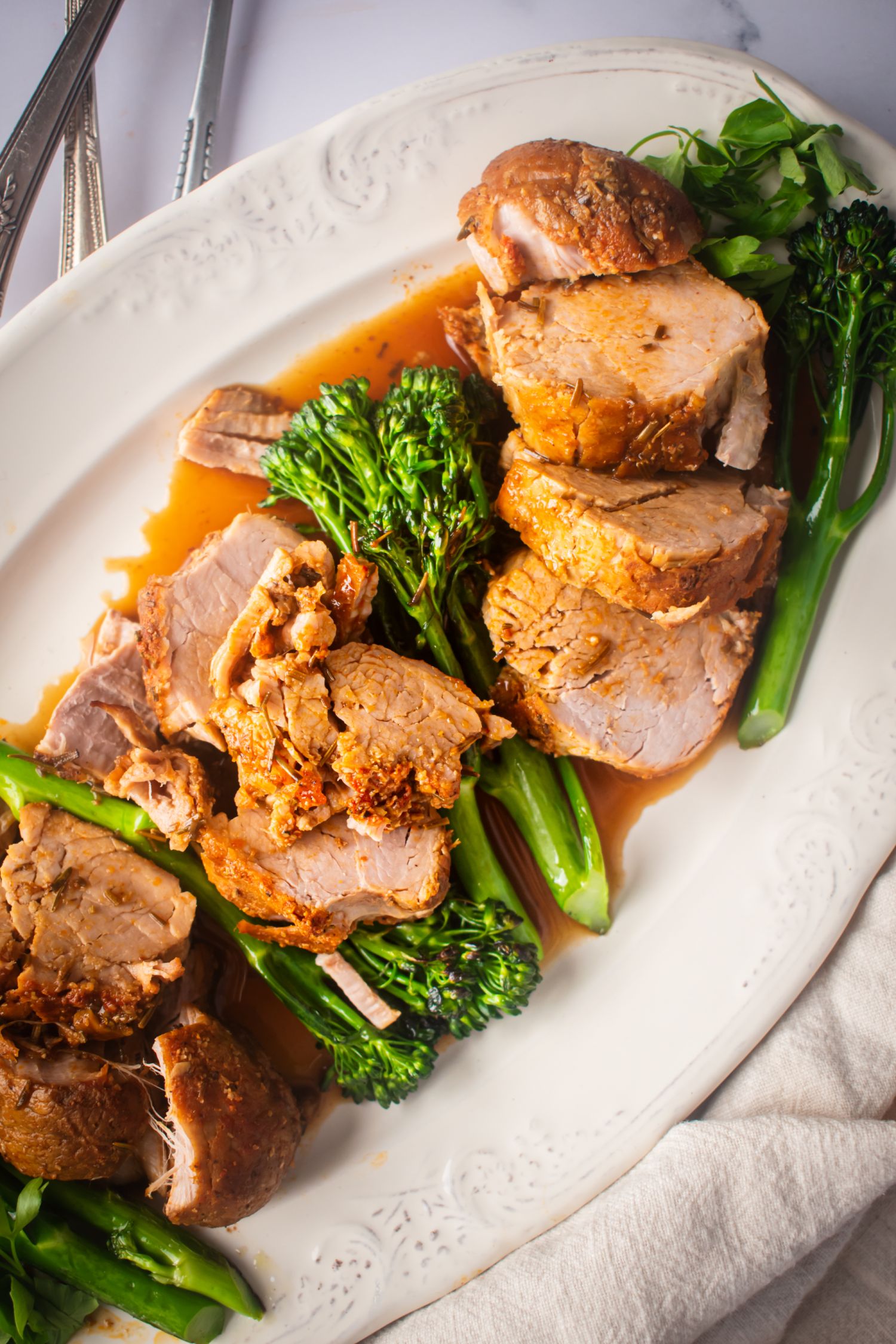 Crockpot pork tenderloin with a balsamic sauce on a plate with brococli.