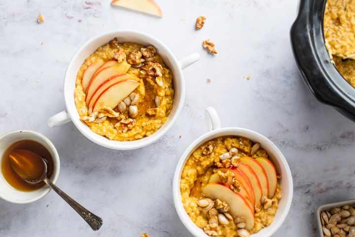 Slow cooker steel cut oatmeal with pumpkin pie spices on a plate with sliced banana.