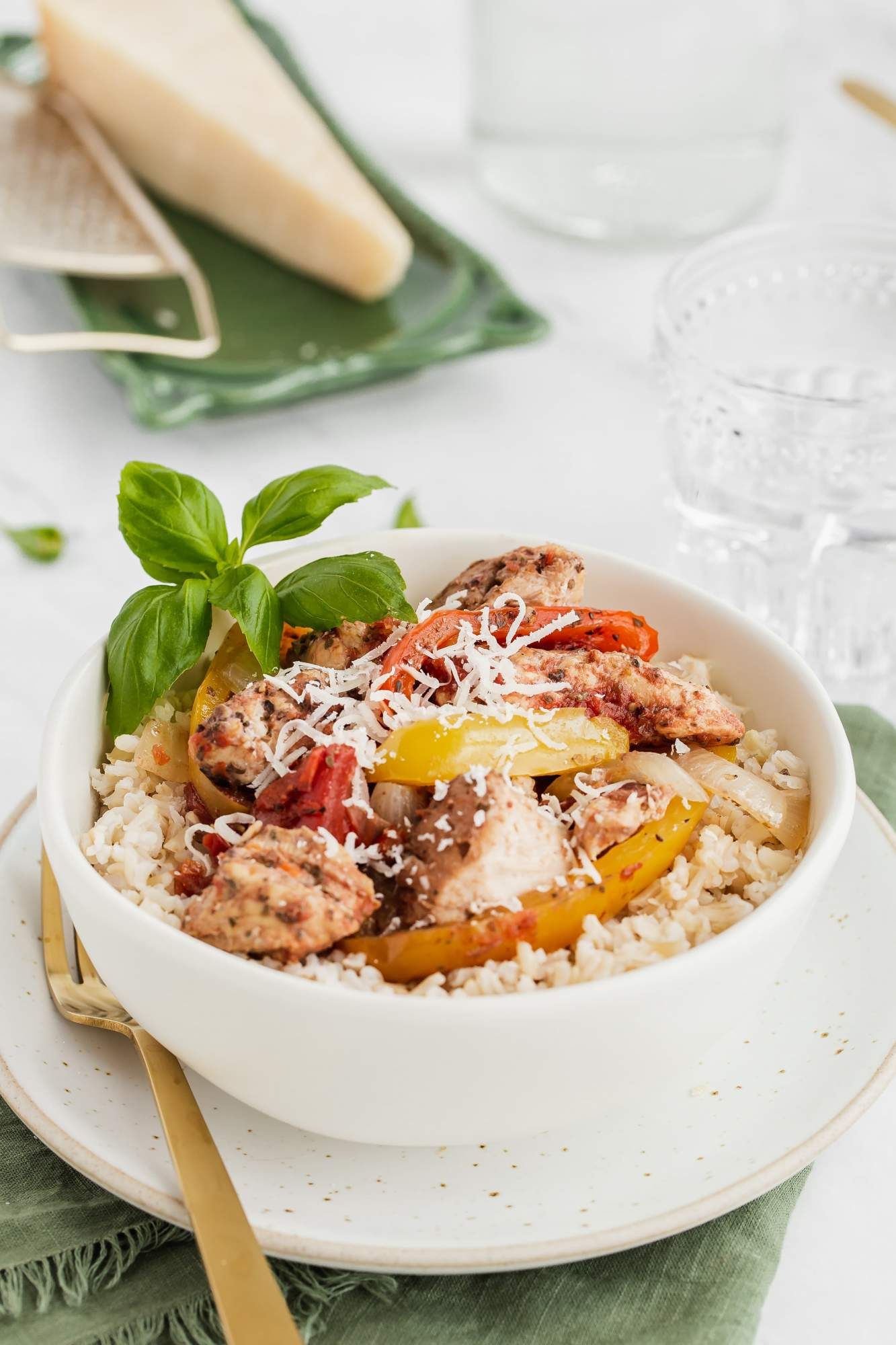 Italian chicken with red peppers, spices, and chicken breast in a bowl with rice and Parmesan cheese.