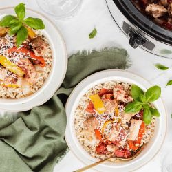 Slow cooker red pepper Italian chicken in a bowl with cooked chicken breast, bell peppers, garlic over white rice.