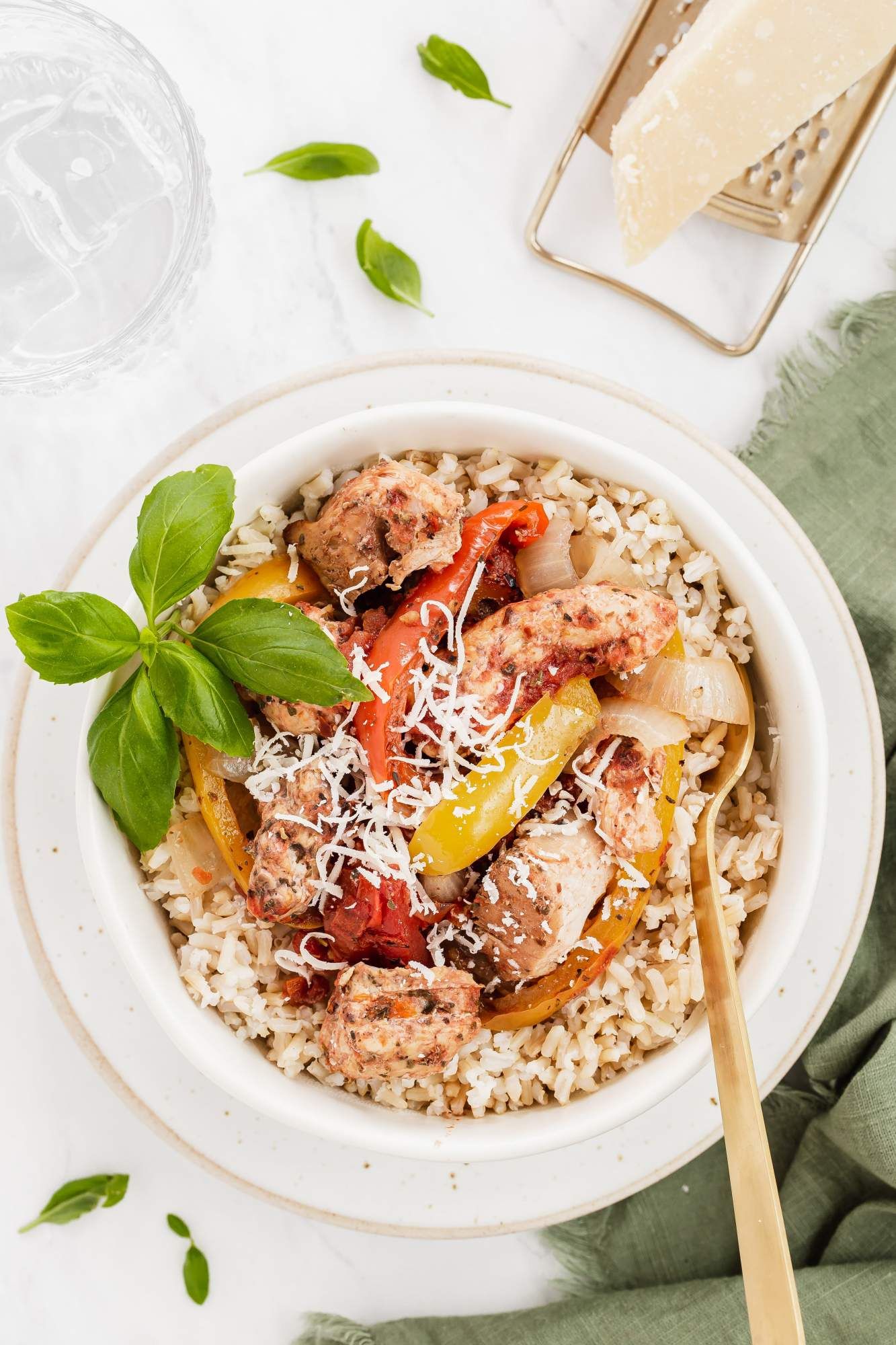 Red pepper chicken that was slow cooked with chicken breast, tomatoes, and red peppers in a bowl with Parmesan cheese.