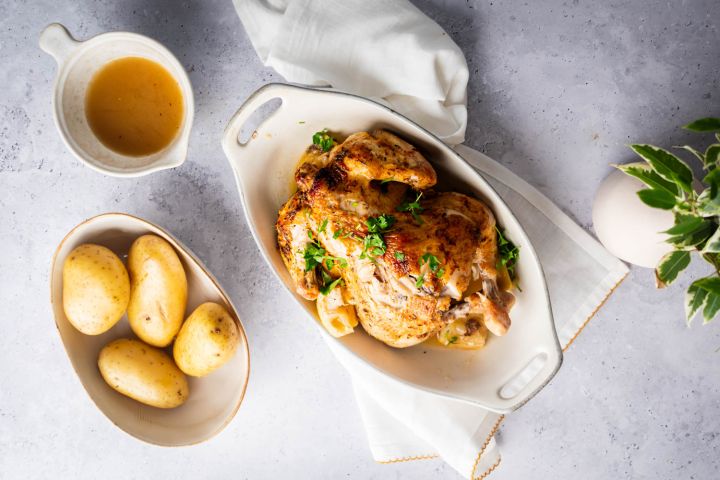 Slow cooker rotisserie chicken with a homemade spice rub, lemon, and parsley with potatoes on the side.