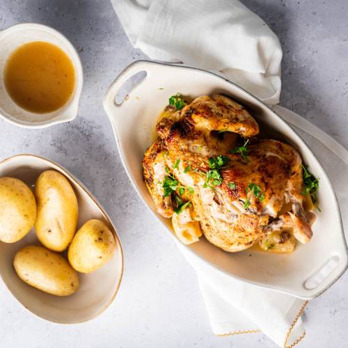 Slow cooker rotisserie chicken with a homemade spice rub, lemon, and parsley with potatoes on the side.