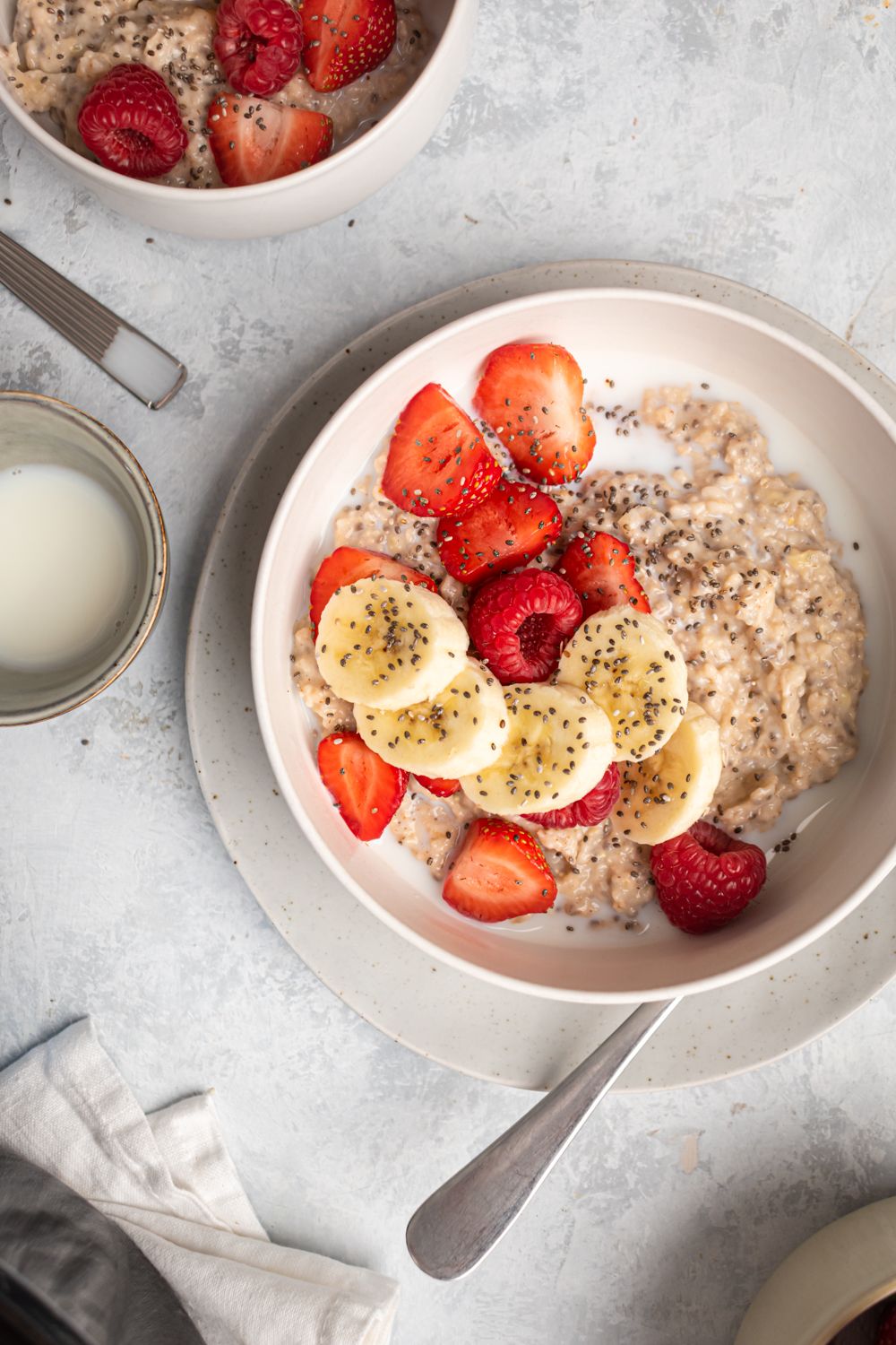 Steel cut oats cooked in the crockpot and served in a bowl with bananas, strawberries, raspberries, and milk.