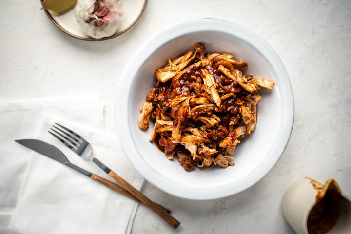 Slow cooker sweet and spicy chicken with soy sauce, Asian chili paste, and ginger in a bowl.