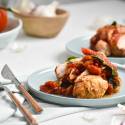 Slow cooker tomato balsamic chicken sliced and served with spinach and basil on a plate.