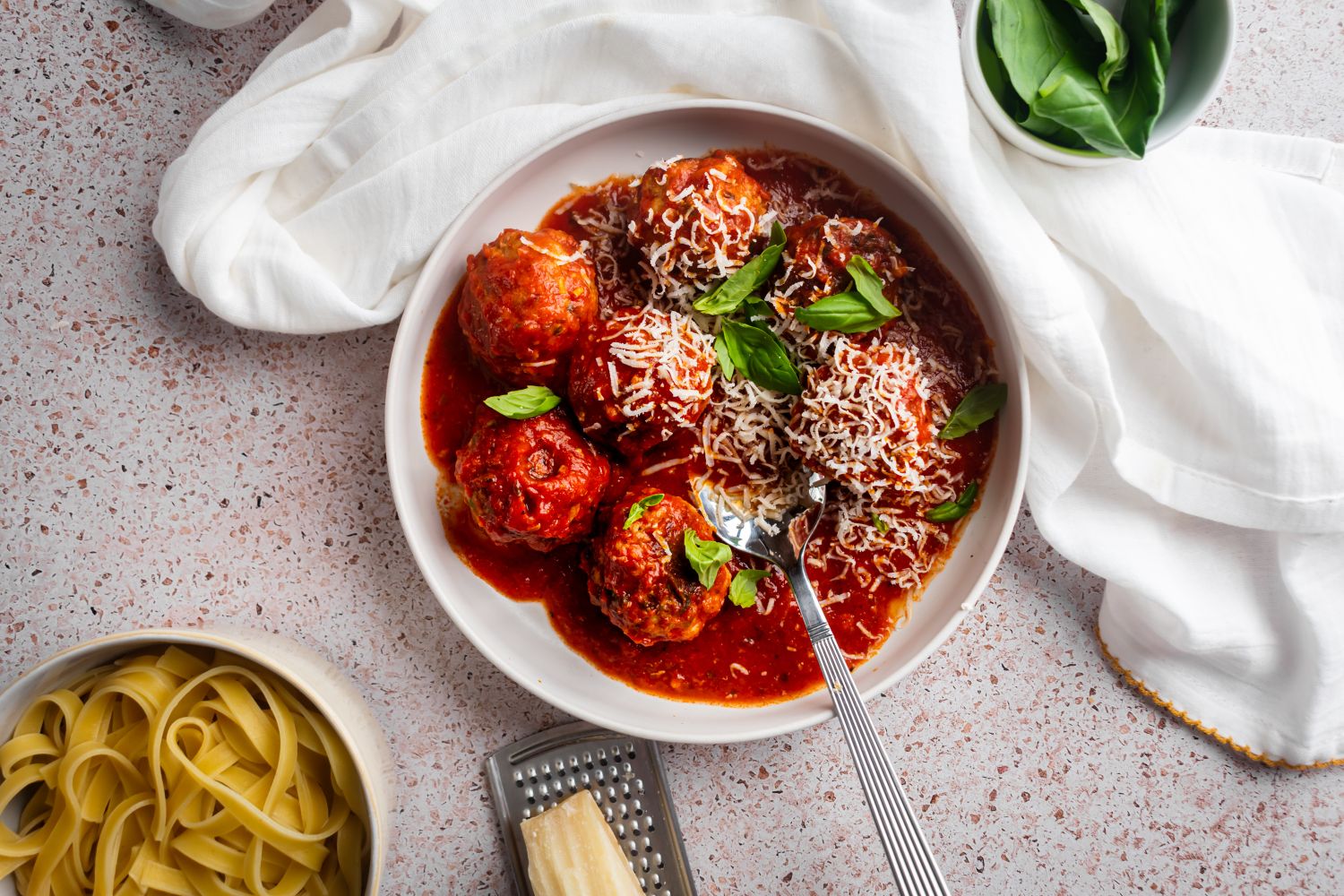 Slow cooker turkey meatballs in a shallow bowl with marinara sauce, fresh basil, and Parmesan cheese. 