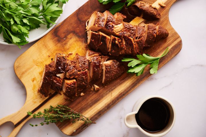 Slow cooker turkey breast tenderloin sliced on a wooden cutting board.