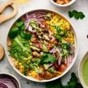 Southwest chicken and rice bowl with grilled chicken, corn, onion, tomatoes, rice, and cilantro yogurt sauce.