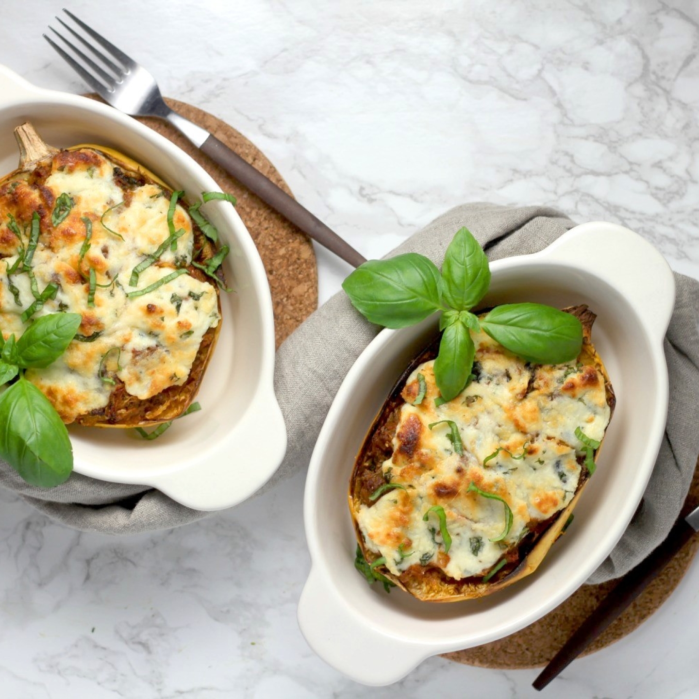 Spaghetti squash lasagna boats in two casserole dishes with basil.