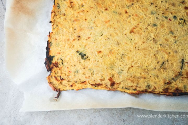 Spaghetti squash pizza crust baked until crispy on parchment paper.