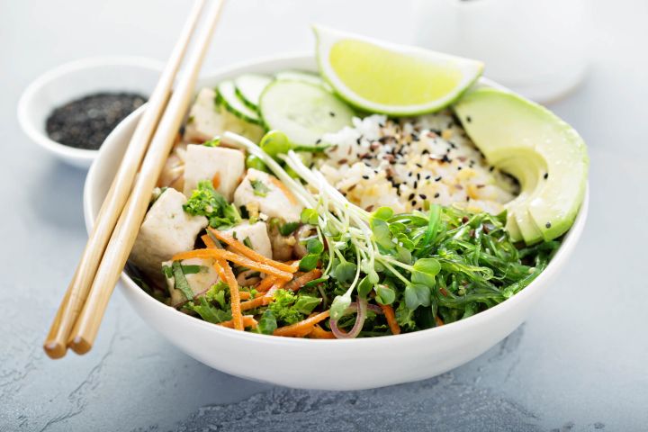 Vegetarian sushi bowl with avocado, rice, seaweed, edamame, and tofu.