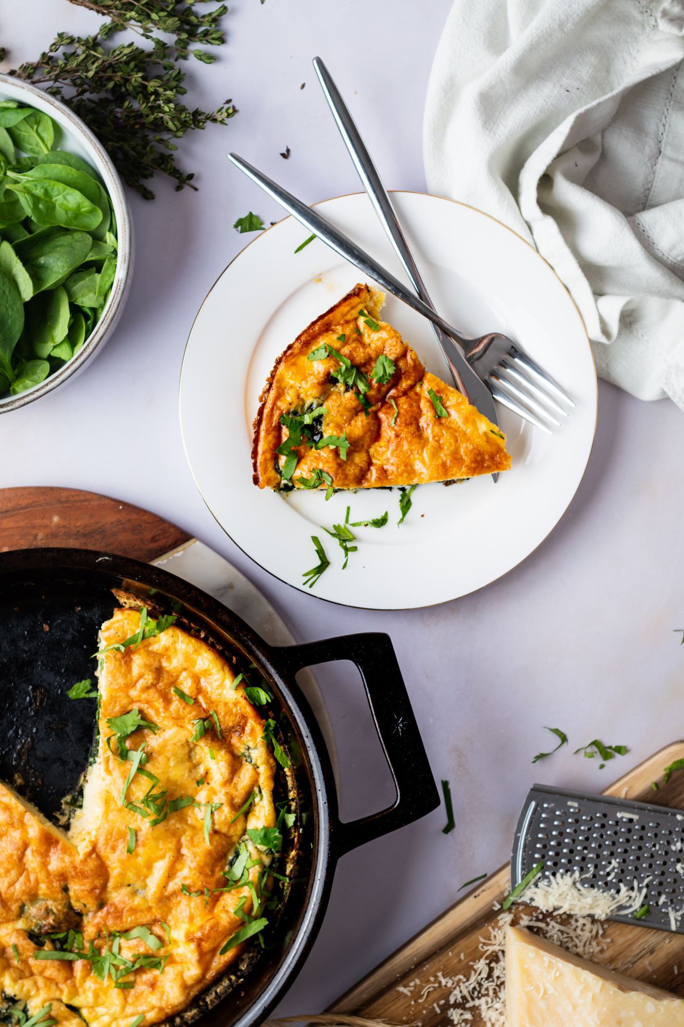 Cheesy spinach frittata with eggs, baby spinach, cheddar cheese, and Parmesan cheese in a skillet.