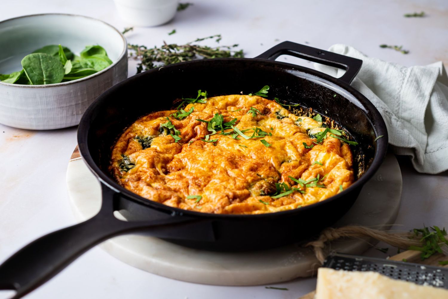 Frittata with spinach, eggs, and cheese in a vast iron skillet with fresh herbs.