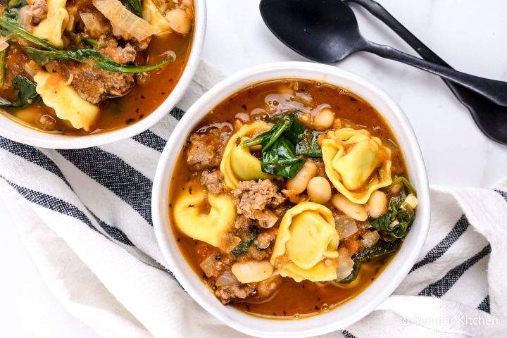 Spinach tortellini soup in a bowl with ground turkey, spinach, white beans, and tomatoes in a white bowl.