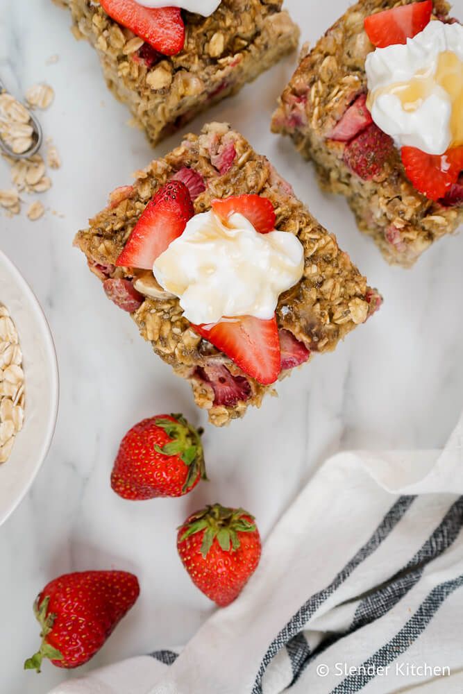 Baked oatmeal with bananas and strawberries cut on a marble board with yogurt and honey.