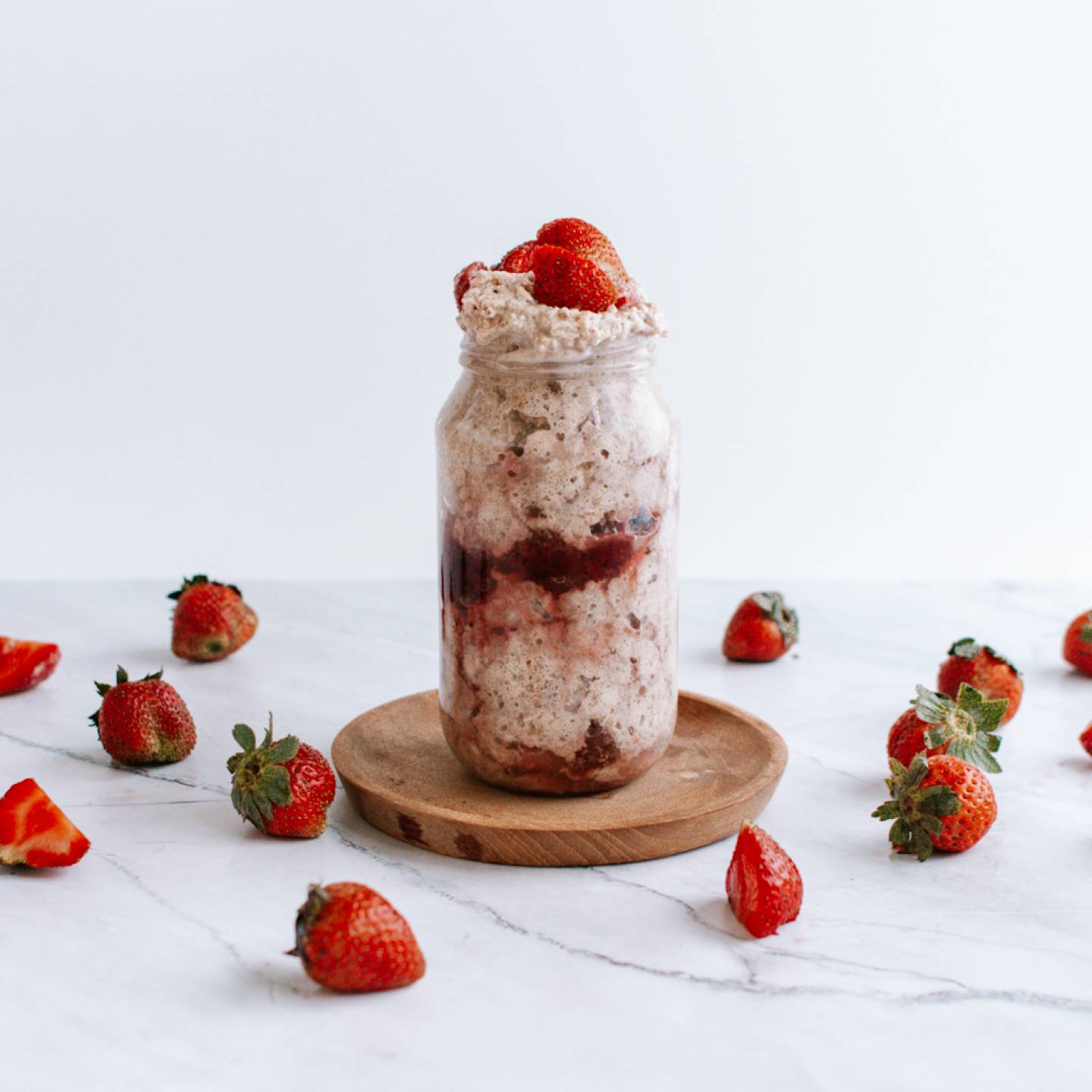 Strawberry overnight oatmeal with rolled oats and chia seeds in a mason jar with fresh strawberries and cream.