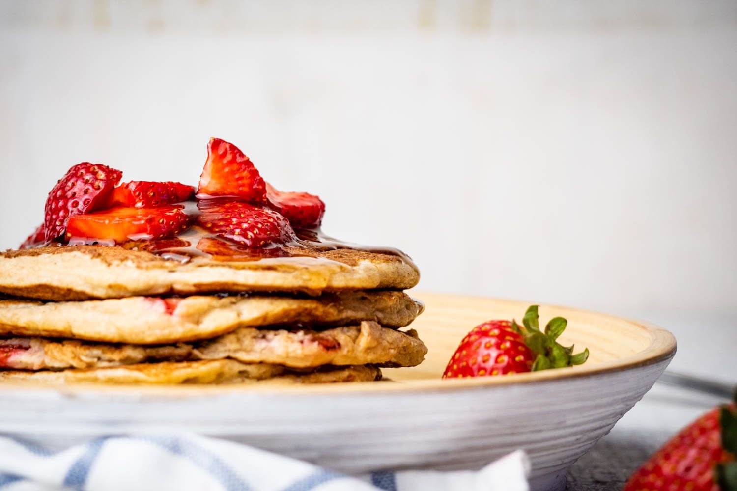 Strawberry oatmeal pancakes with bananas on a white plate.