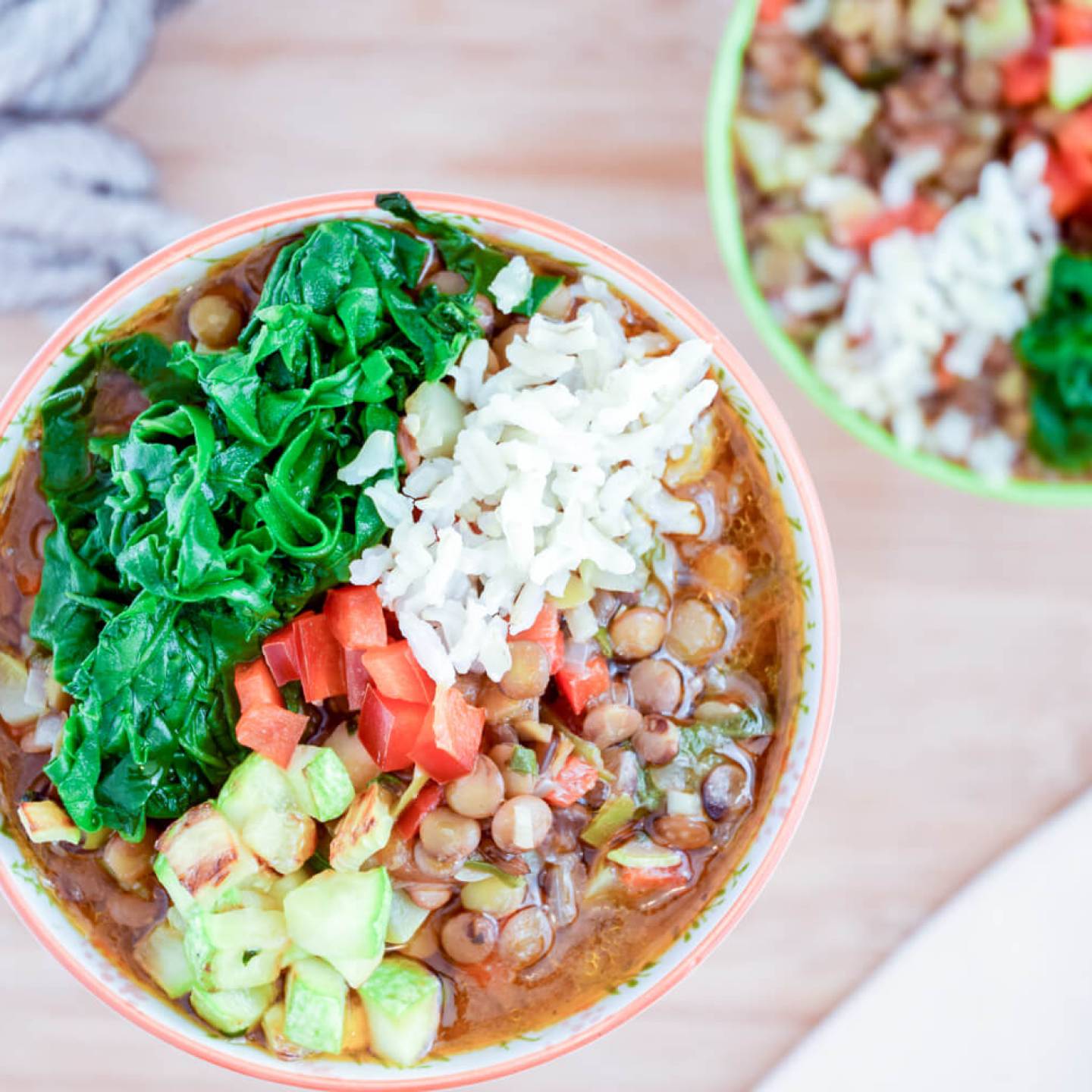 Mexican lentil soup with lentils in a spicy tomato broth served with brown rice, spinach, and zucchini in two bowls.