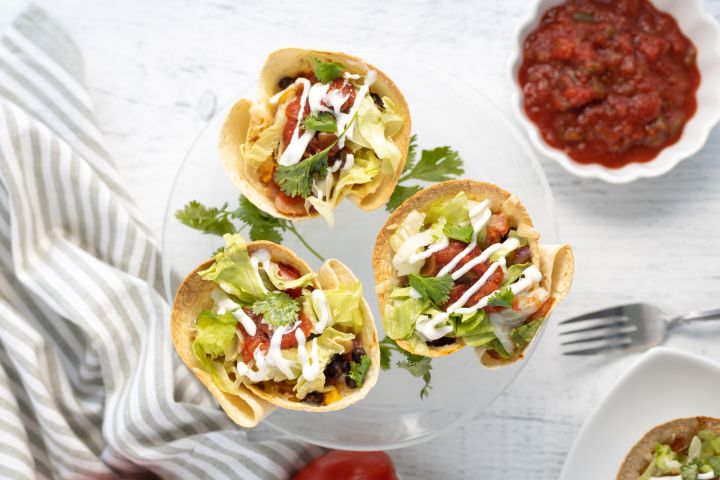 Taco cups with beans, corn, peppers, onions, salsa, and cheese in tortilla cups.