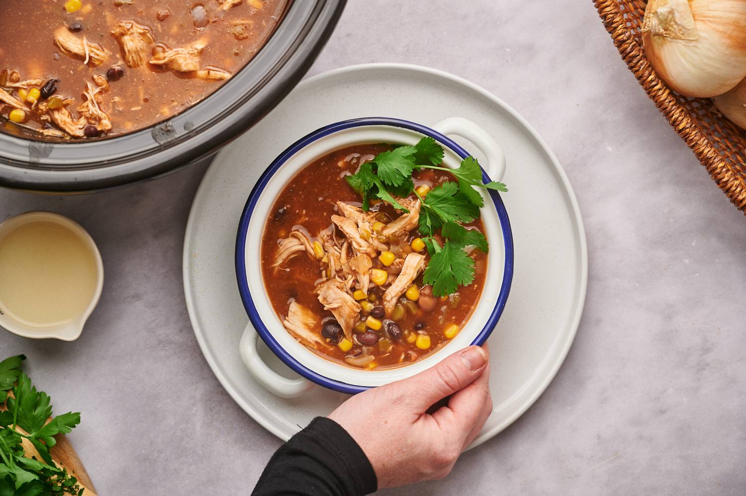 Slow Cooker Taco Soup with shredded chicken, cilantro, cheese, beans, corn, and baked tortilla chips.