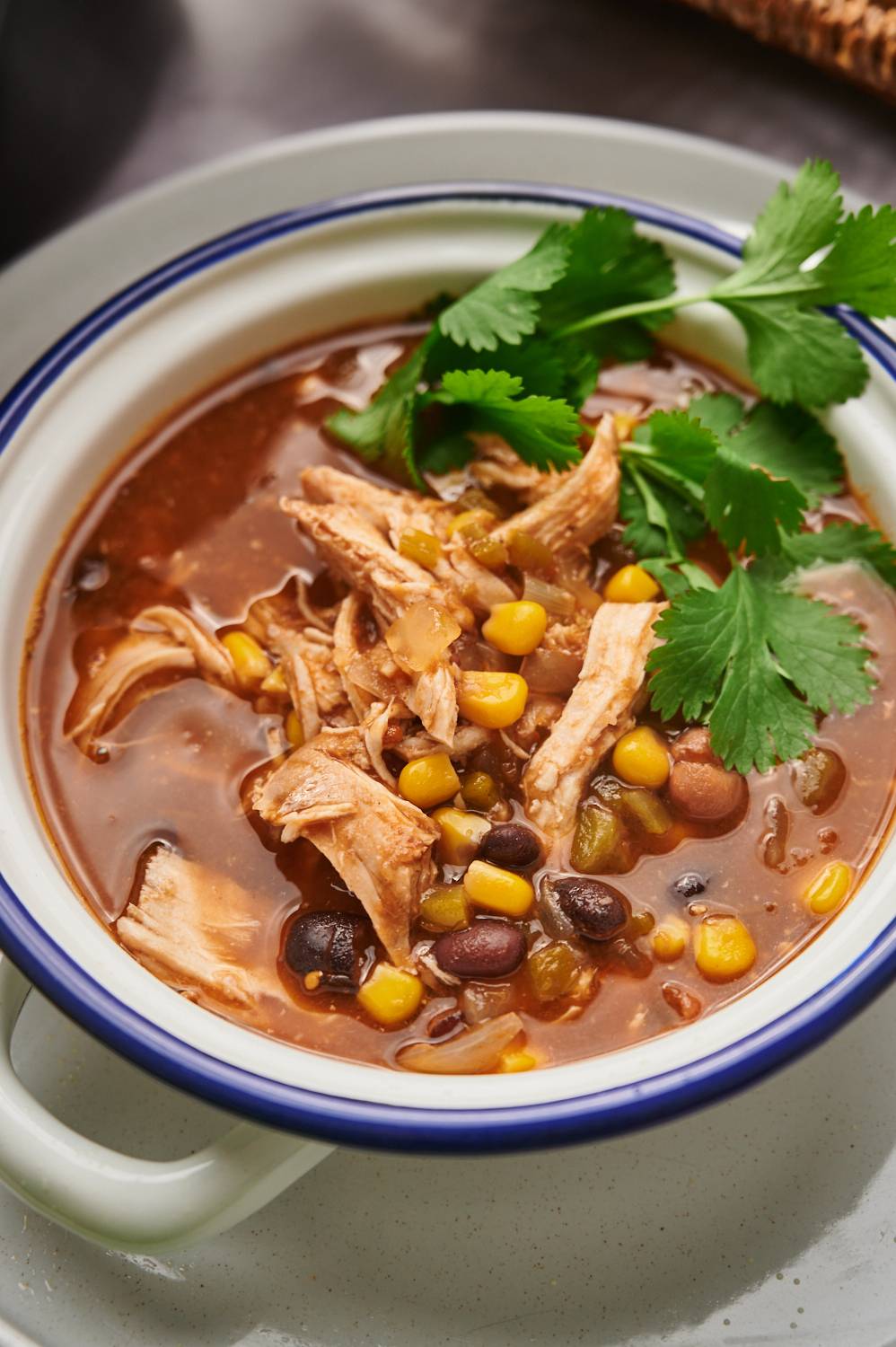 Taco soup made with shredded chicken, beans, corn, onion, and cilantro in a bowl.