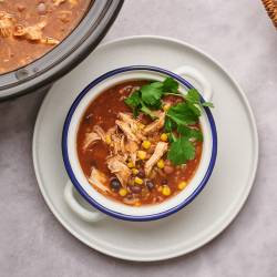 Healthy taco soup with black beans, pinto beans, shredded chicken, cilantro, and cheese.