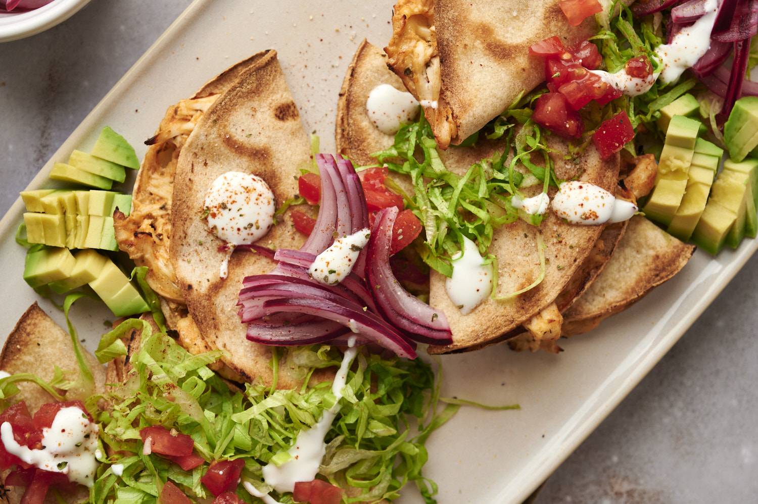 Mexican tacos dorados topped with sour cream, tomatoes, onions, avocado, salsa, and shredded lettuce.