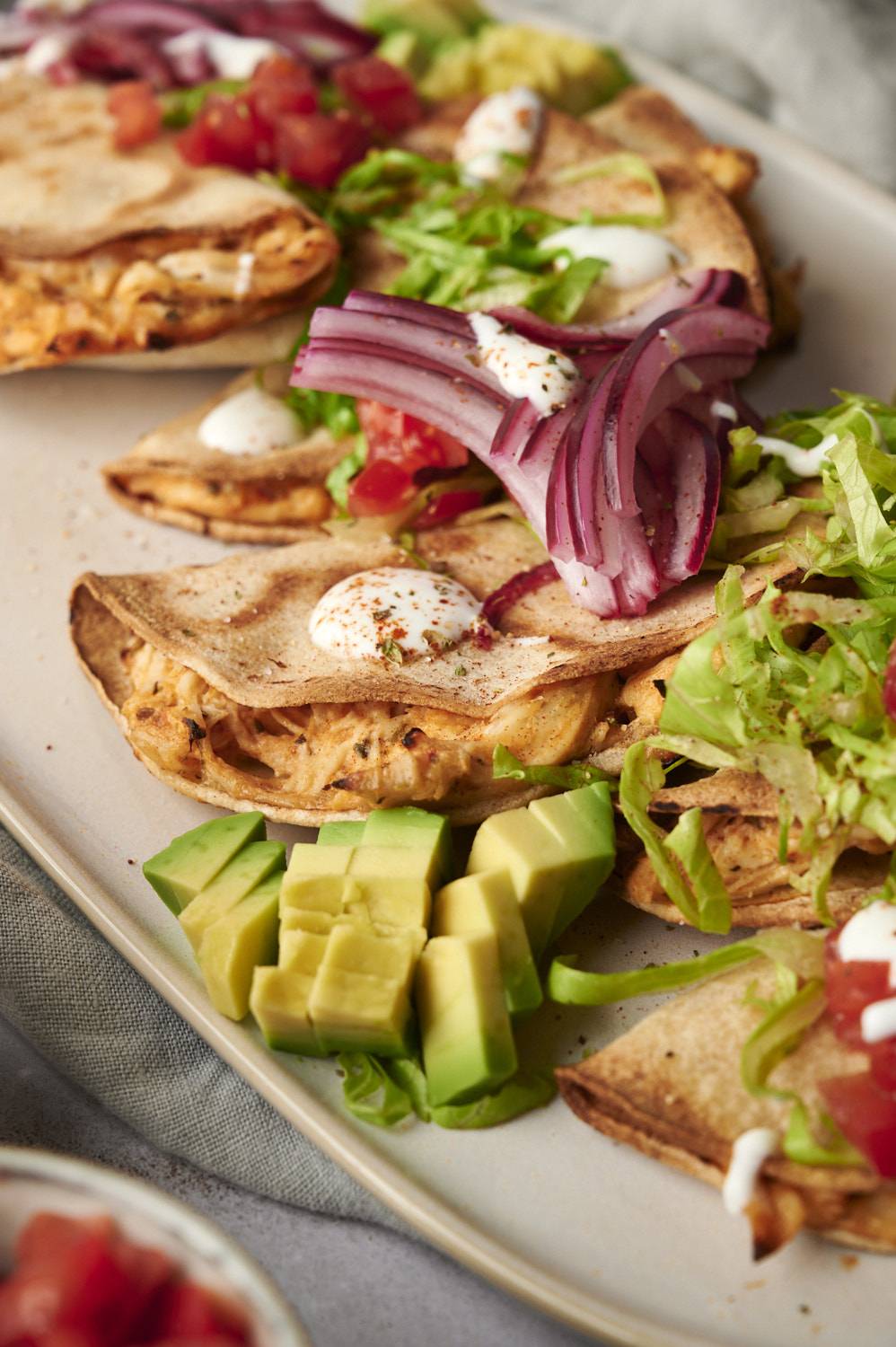 Baked tacos dorados filled with chicken and topped with lettuce, salsa, avocado, red onions, tomatoes, and sour cream.